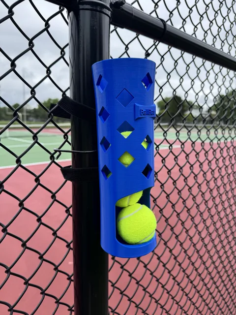 BallBar strapped to a fence post in a backyard with a dog's tennis balls inside